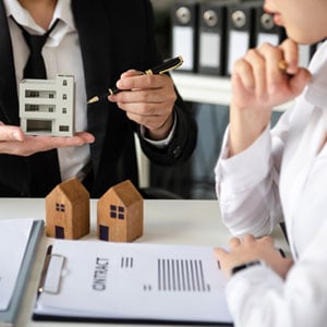 A man and woman holding a model house, symbolizing estate planning - THE LAW OFFICES OF DIANE ANDERSON